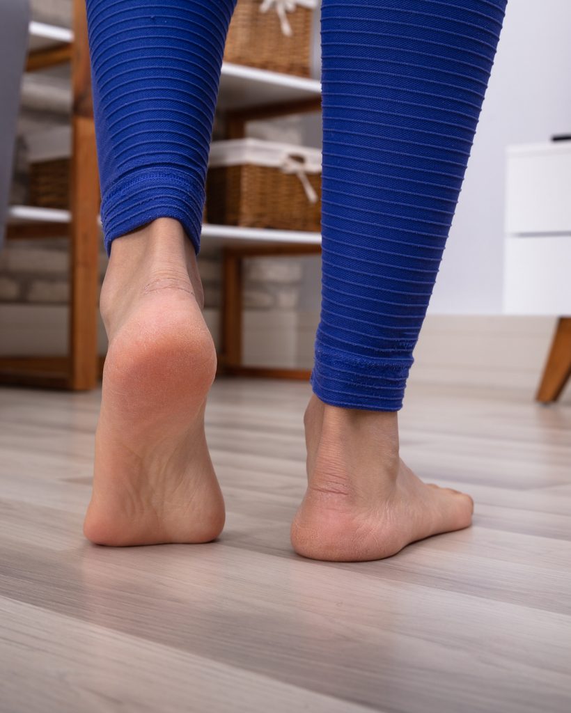 Close-up Of A Woman's Feet Walking On The Hardwood Warm Floor