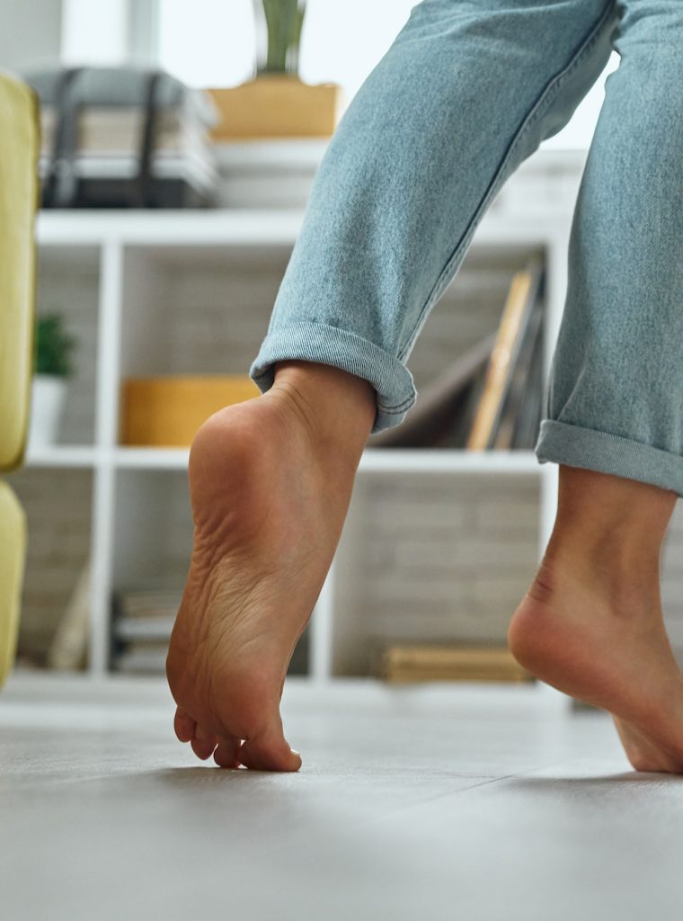 close-up-of-barefoot-woman-walking-on-wooden-floor-at-home